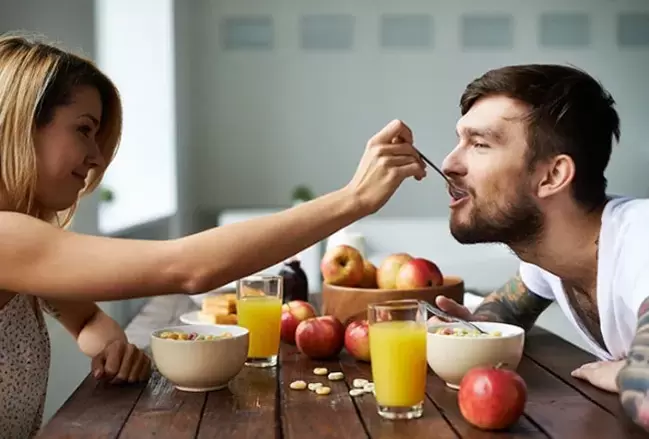 a woman feeds a man with nuts to increase power